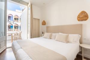 a white bedroom with a large bed and a balcony at Divino Hotel Boutique in Sitges