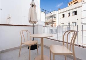 Divino Hotel Boutique في سيتجيس: طاولة وكراسي على شرفة مع مظلة