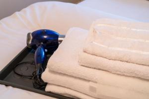 a blue hairdryer sitting next to a stack of towels at Bumble Bee Cottage Witney Serviced accommodation in Witney