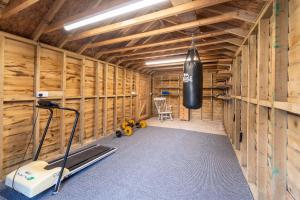 a room with a gym with wooden walls and a treadmill at Bumble Bee Cottage Witney Serviced accommodation in Witney