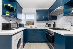 a kitchen with blue cabinets and a washer and dryer at The Holloway Suite- LongTerm Stays 15% Off Sleeps4 in London