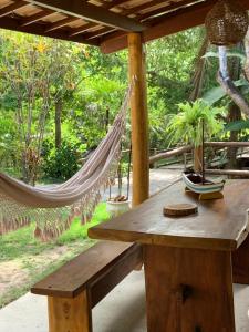 a hammock and a wooden table with a hammock at Sítio Maravilha Parracho e Sonja (Casa Pé Na Areia) in Arraial d'Ajuda