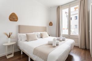 a white bedroom with a white bed and a window at Divino Hotel Boutique in Sitges