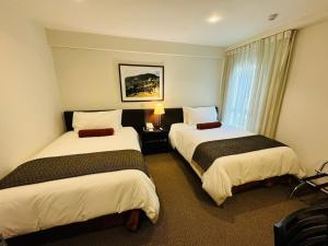 a hotel room with two beds and a window at LP Los Portales Hotel Cusco in Cusco