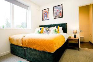 a bedroom with a large bed with an orange blanket at Classy Modern Flat: Free Parking, Gym & Roof Garden in Stevenage