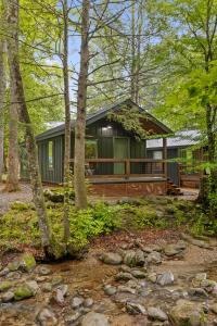 una cabaña en el bosque con un arroyo frente a ella en Roamstead Smoky Mountains en Cosby