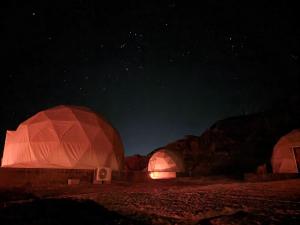 two domes in the desert lit up at night at Wadi Rum stargazing camp in Wadi Rum
