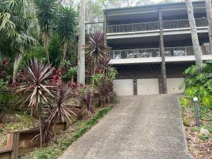 una entrada que conduce a una casa con palmeras en Palm beach Sydney, Modern home with water view en Palm Beach