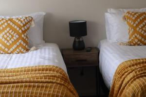 2 Betten in einem Zimmer mit einer Lampe auf einem Nachttisch in der Unterkunft Canonbar Motel in Nyngan