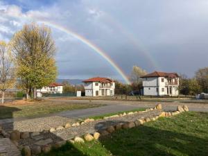 Ein Regenbogen am Himmel über einigen Häusern in der Unterkunft Къща за гости В 12 и 5 in Dolna Banya