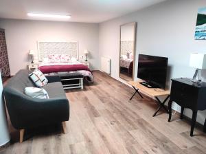 uma sala de estar com uma cama, um sofá e uma televisão em CASA Loft Argoños em Argoños