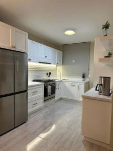 プエルト・モレロスにあるCasa Pelicanoの白いキャビネットとステンレス製の電化製品を備えたキッチン