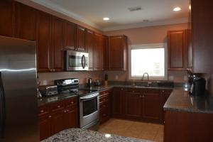 Large Private Room with Balcony and bathroom في تشارلستون: مطبخ مع خزائن خشبية وثلاجة من الفولاذ المقاوم للصدأ