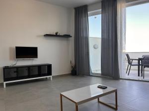 uma sala de estar com uma televisão e uma mesa de centro em Qawra penthouse 4person AC+wifi em St. Paul's Bay