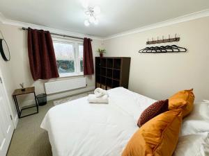 Un dormitorio con una gran cama blanca con almohadas naranjas. en Riverview, en Colchester 5 fotos más