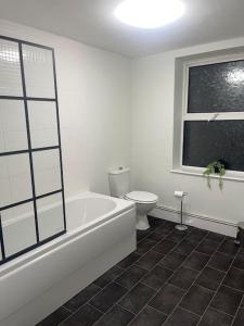 a white bathroom with a toilet and a bath tub at Modern 2 Bed in the heart of Maidstone in Kent