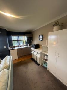 a kitchen with white cabinets and a white couch at Beach Apartment in Papamoa