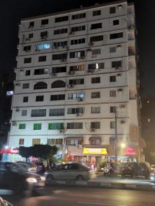 un grand bâtiment blanc avec des voitures garées devant lui dans l'établissement Luxury Apartment near cairo airport, au Caire