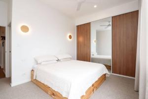 a white bedroom with a bed and a mirror at Palm Springs in Port Lincoln! in Port Lincoln