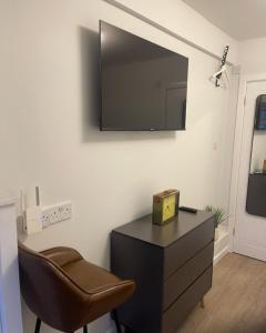 a room with a chair and a dresser with a television on the wall at Private En-suite in Birmingham