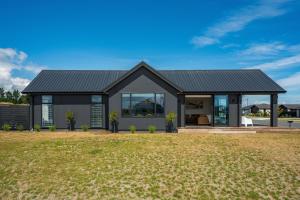 una casa con techo negro y patio en Harakeke Holiday Haven - Taupo, en Taupo