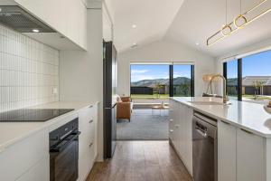 a kitchen with white cabinets and a large window at Harakeke Holiday Haven - Taupo in Taupo
