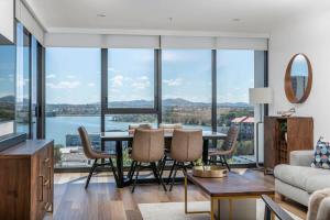 ein Wohnzimmer mit einem Tisch und Stühlen mit Aussicht in der Unterkunft Sensational City Apartment with Lake Views - Benjamin Way ACT in Canberra