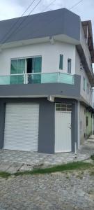 una casa blanca con dos puertas de garaje en una calle en Casa acessível en Dias dʼÁvila