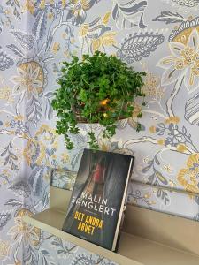 ein Buch auf einem Regal neben einer Pflanze in der Unterkunft The Solhem Cabin in Strömstad