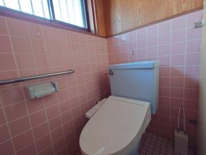 a bathroom with a toilet in a pink tiled wall at 39guest house in Ibusuki