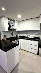 a kitchen with white cabinets and a black counter top at Apartamento en segundo piso Zafiro C, Valle del Lili. in Cali
