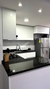 a kitchen with white cabinets and a black counter top at Apartamento en segundo piso Zafiro C, Valle del Lili. in Cali