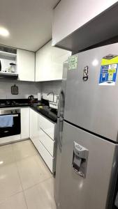 a kitchen with a stainless steel refrigerator and white cabinets at Apartamento en segundo piso Zafiro C, Valle del Lili. in Cali