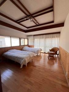 a large room with two beds and a chair at 39guest house in Ibusuki