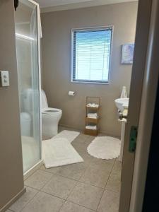 a bathroom with a shower and a toilet and a sink at Beach Apartment in Papamoa