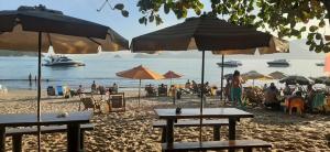 a beach with umbrellas and people sitting on the sand at Suíte em casa particular Sidi & Val - Soul Almada - Praia da Almada Ubatuba in Ubatuba