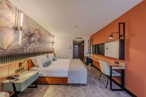 アンタルヤにあるベストウエスタン プラス カーン ホテルの大きなベッドとデスクが備わるホテルルームです。