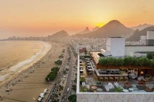 a view of a beach and a city at sunset at Hilton Copacabana Rio de Janeiro in Rio de Janeiro