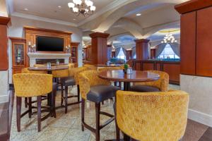 um restaurante com mesas e cadeiras e uma televisão em Drury Plaza Hotel St. Louis Chesterfield em Chesterfield