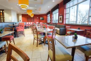 Drury Inn & Suites Columbus Grove City في غروف سيتي: مطعم بطاولات وكراسي ونوافذ