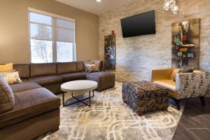 a living room with a couch and a tv on a brick wall at Drury Inn & Suites Louisville North in Louisville