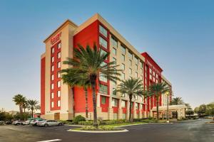 un edificio rojo con palmeras frente a un aparcamiento en Drury Inn & Suites Orlando near Universal Orlando Resort, en Orlando