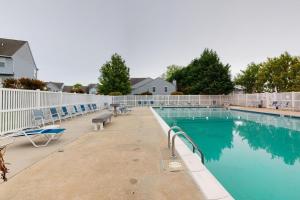 a swimming pool with chairs and a fence around it at Stylish 2BR Condo Near Beach, Large Pool & Patio, Pet Friendly in Rehoboth Beach