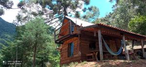 a log cabin in the woods with a swing at Chalé serra azul in São Bento do Sapucaí