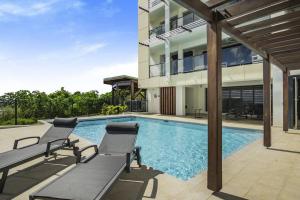 a swimming pool with two chairs and a house at Appartement Corail Bleu in Fort-de-France