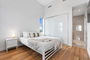 ein weißes Schlafzimmer mit einem weißen Bett und einem Fenster in der Unterkunft Absolute Beachfront 3 Bedroom Penthouse Bokarina Sunshine Coast in Kawana Waters