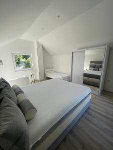 1 cama blanca grande en una habitación con espejo en Vikendica u prirodi na ranču, en Zolaći