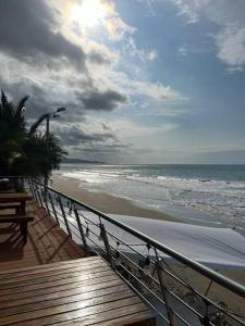 een uitzicht op een strand met de oceaan en een houten terras bij Apartamento en Resort Playa Azul in Tonsupa