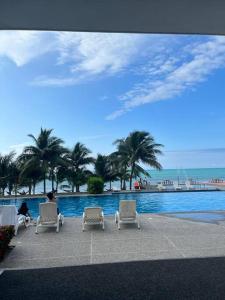 twee personen in stoelen naast een zwembad bij Apartamento en Resort Playa Azul in Tonsupa