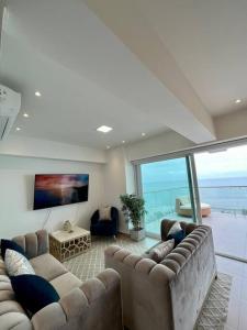 een woonkamer met banken en uitzicht op de oceaan bij Apartamento en Resort Playa Azul in Tonsupa